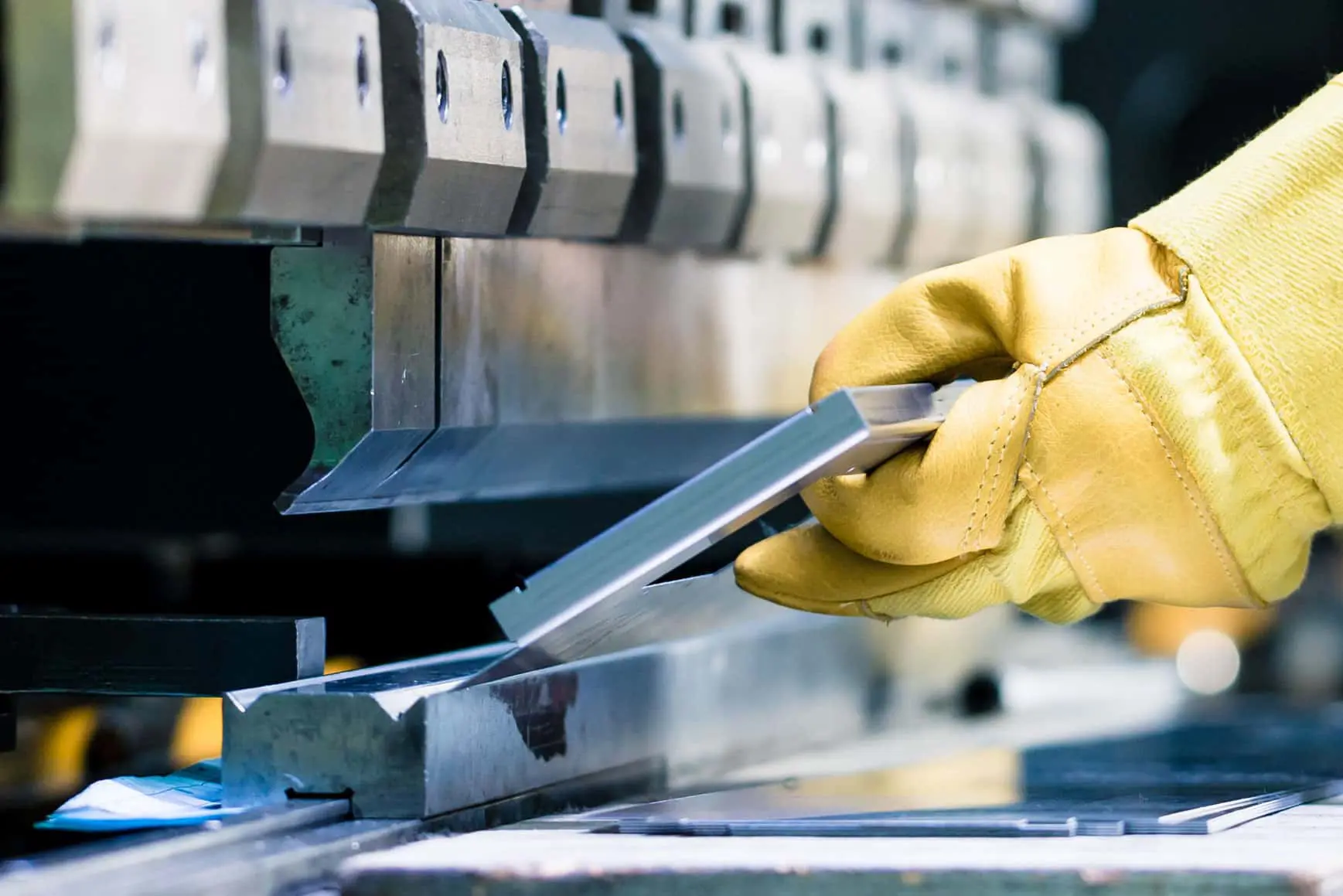 Image of gloved hands holding a piece of metal on a pressbrake