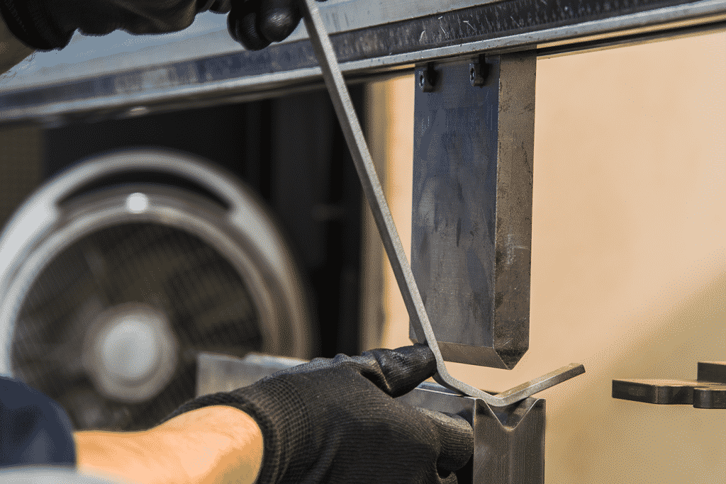 Close up of hands putting a piece of metal up to press brake tooling to fold