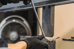Close up of hands putting a piece of metal up to press brake tooling to fold