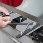 Image of hands attaching the squaring arm onto a press brake