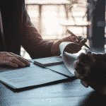 Image of two people reviewing documents and cash